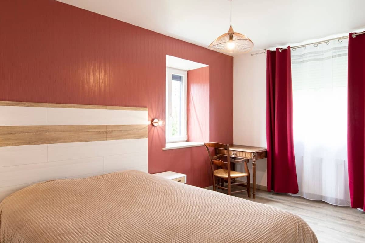 A bedroom with a bed, a desk, and a chair.