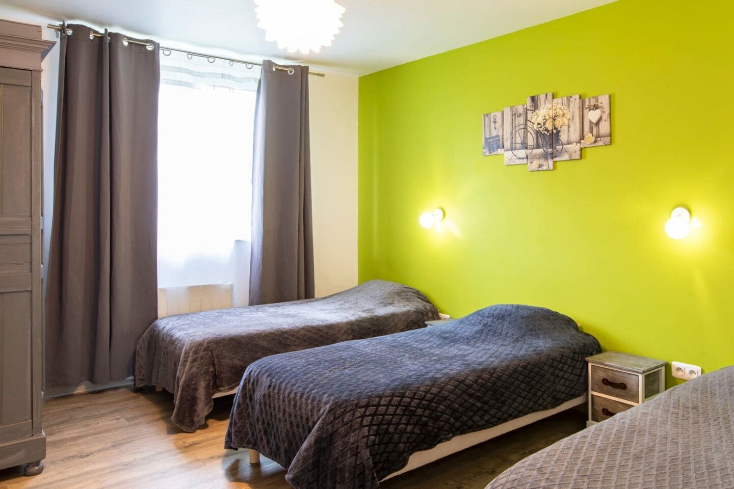 Een kamer met twee bedden, een kledingkast en een groene wand met decoratie.