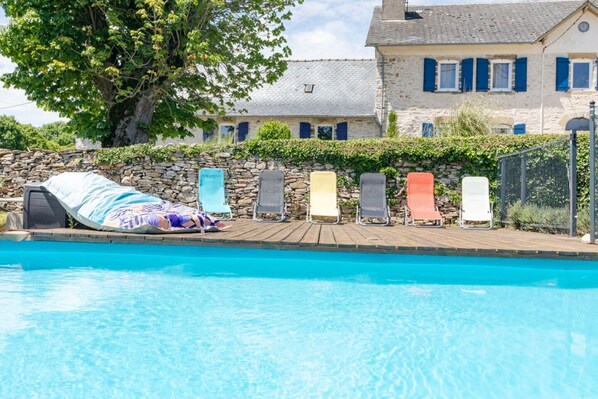 A swimming pool with lounge chairs and a stone wall. - Les gîtes de la commanderie de SaintJean (Beynat)