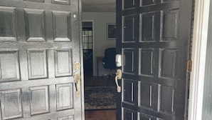 A view through open double doors into a room with a wooden floor and a rug. - The Cardinal House 1A. In a Stunning area, see the deer pass by! (Savannah)