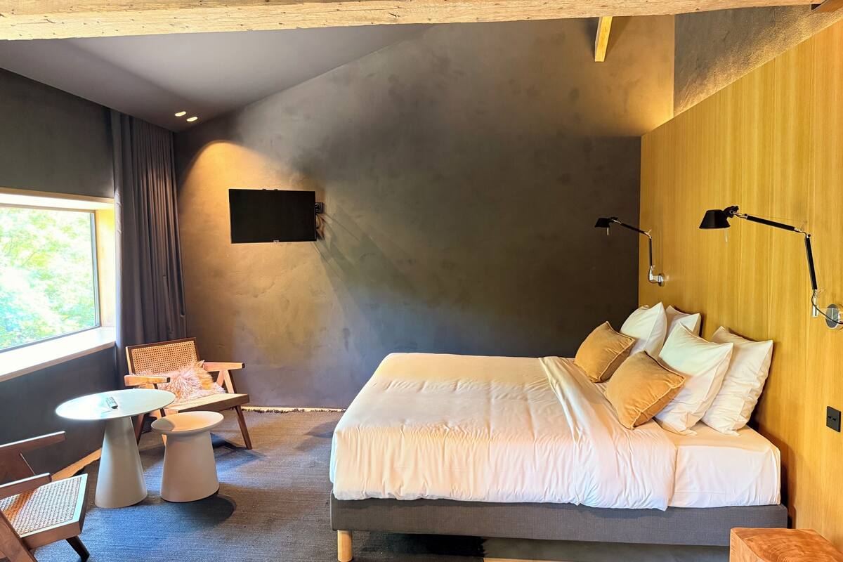A bedroom with a bed, bedside tables, a desk, and a chair.