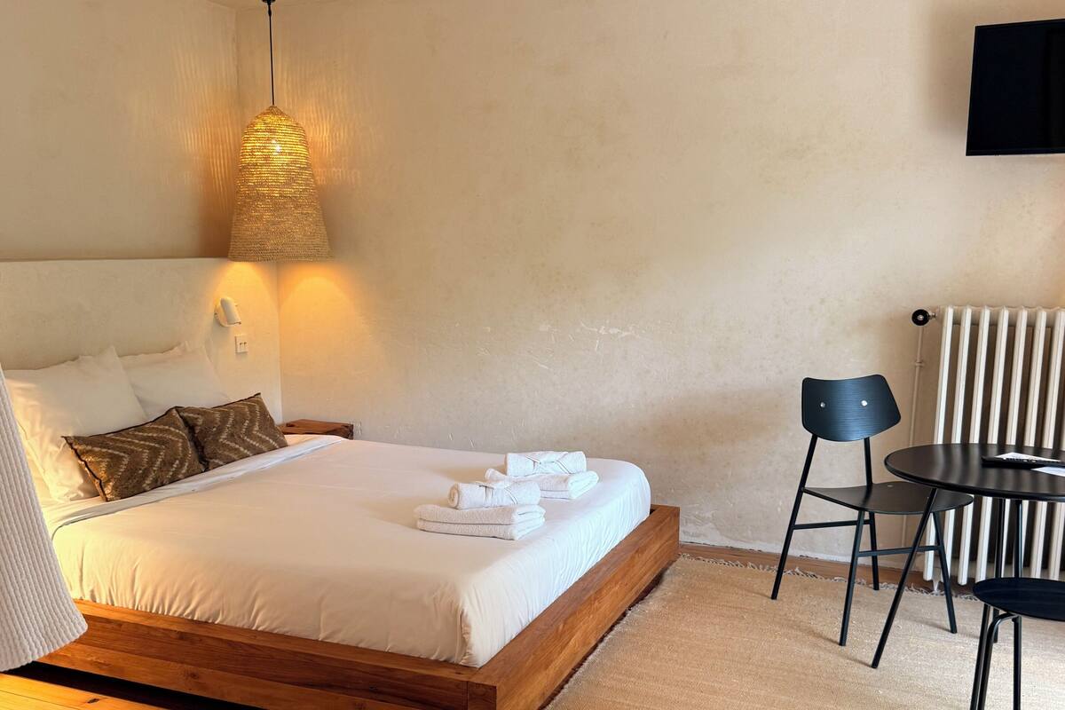 A bedroom with a wooden bed, a round table, and a chair.