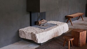 Una chimenea moderna con base de piedra y leña de madera.