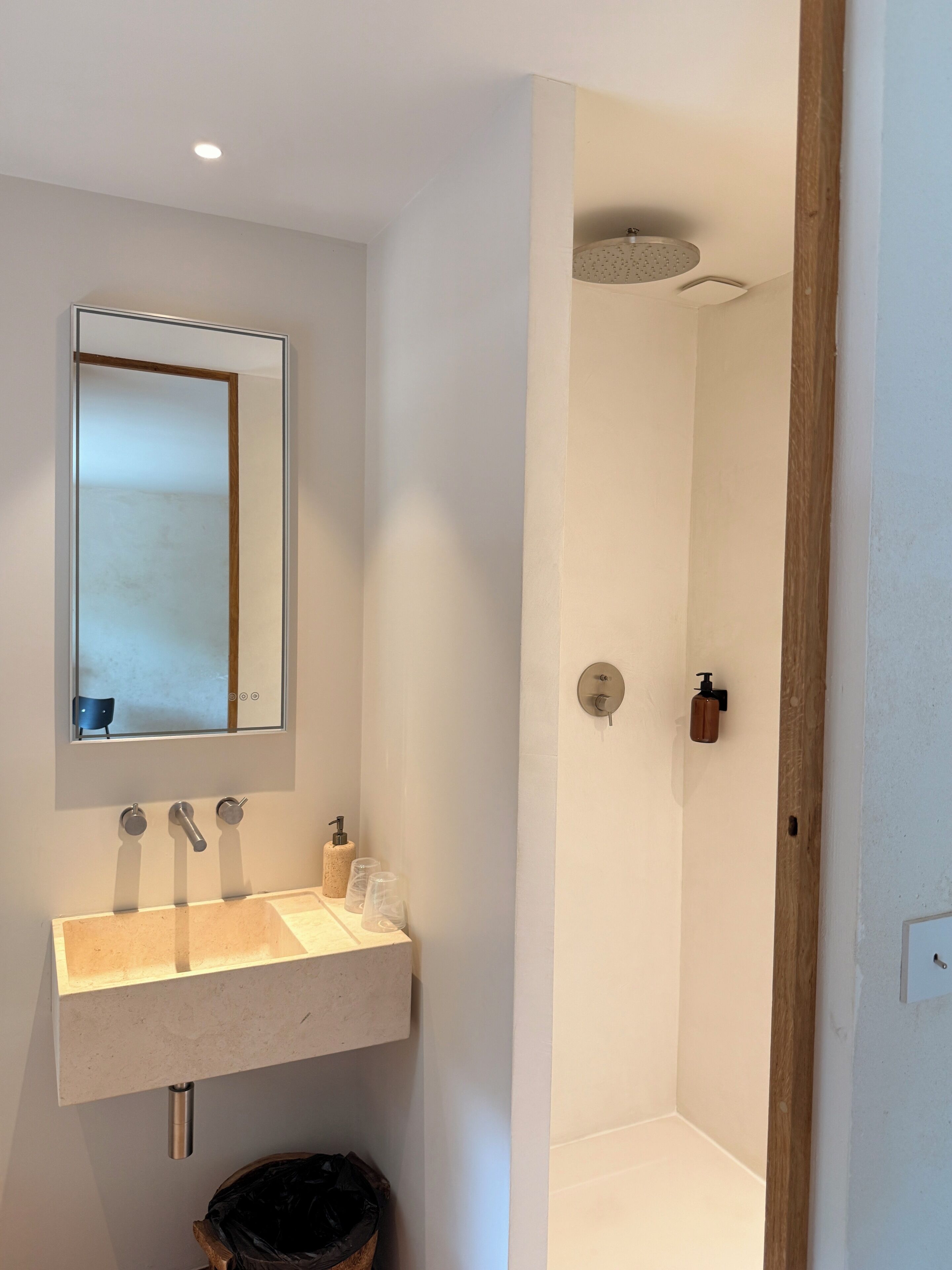 Une salle de bain moderne avec un grand miroir, un lavabo et une douche.