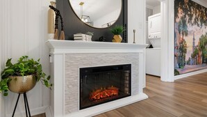 Un salón moderno con chimenea, un espejo grande y un cuadro en la pared.