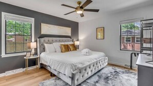 Un dormitorio con una cama grande, ventilador de techo y vistas al exterior.