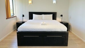 Een moderne slaapkamer met een groot bed, twee nachtkastjes en twee wandlampen.