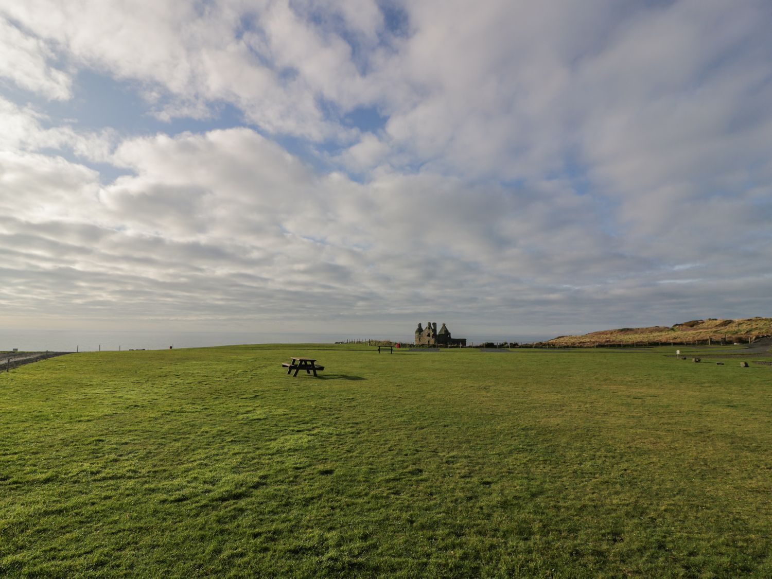 Een grasveld met een picknicktafel en een historisch gebouw in de verte.