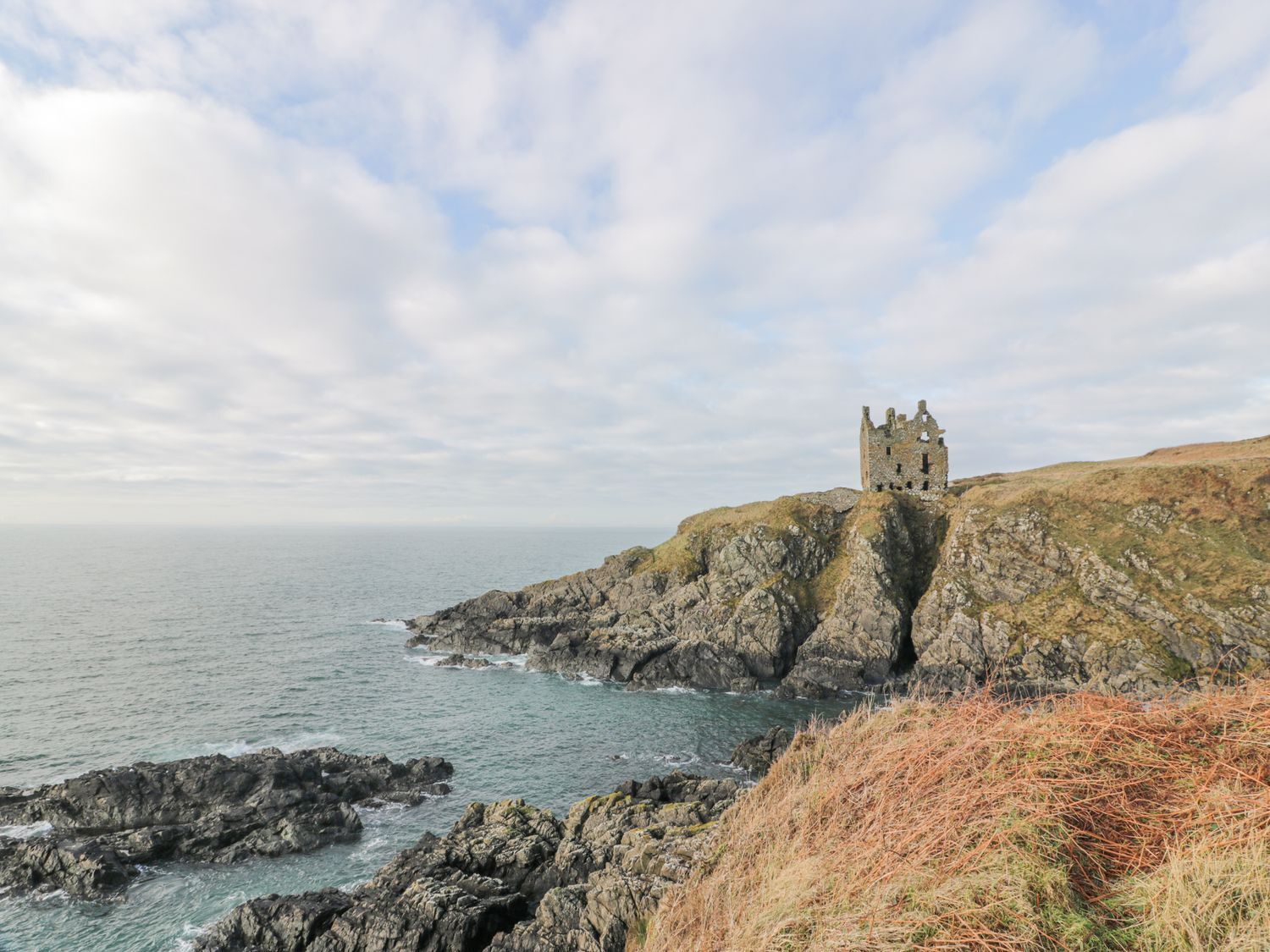 A coastal castle on a rocky cliff overlooking the sea.