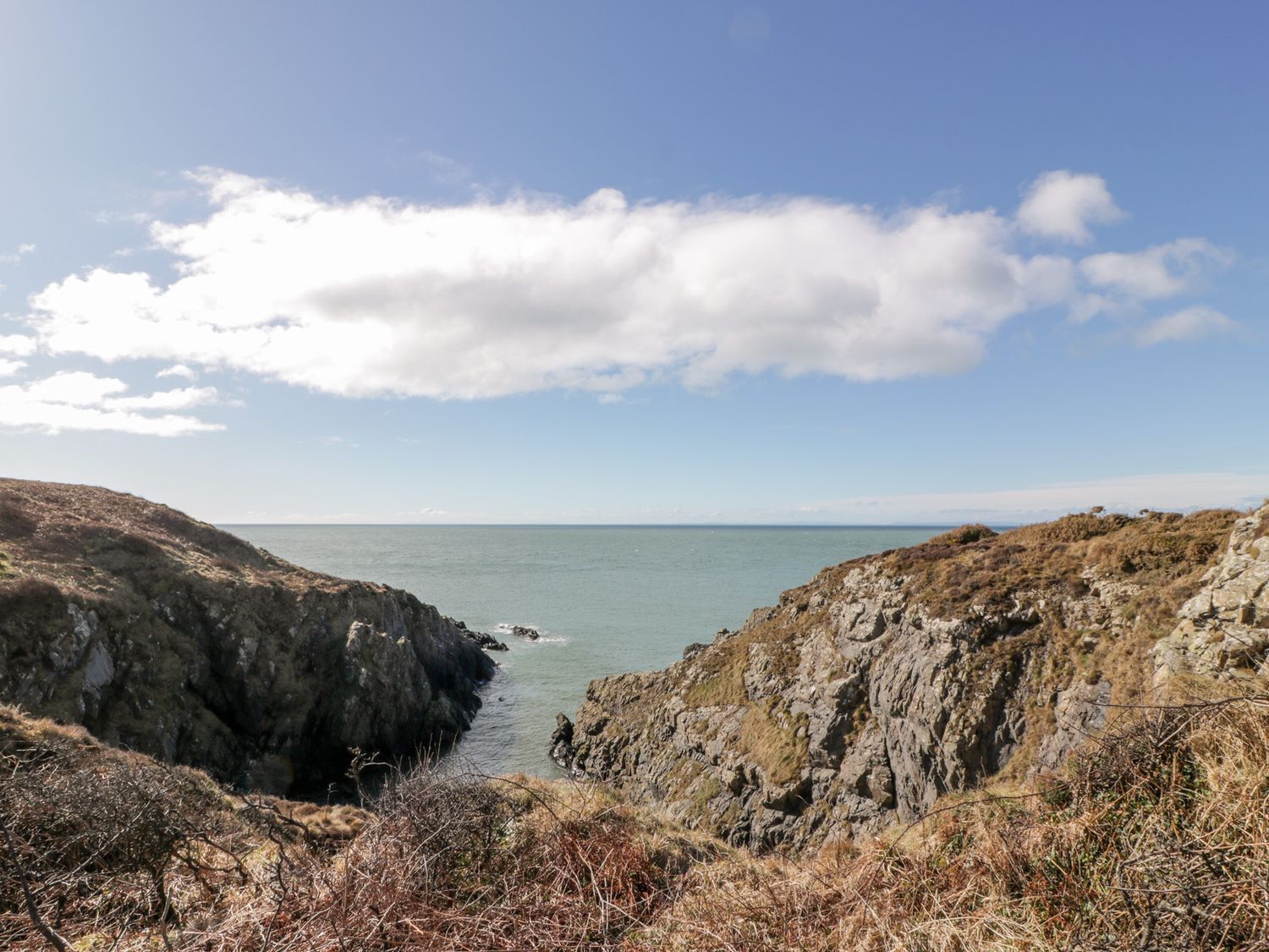 A coastal landscape with rocky cliffs and a clear sky.