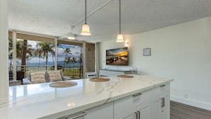 A kitchen with a large island, white cabinets, and pendant lights.