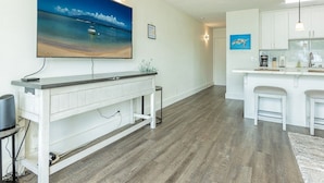 A modern kitchen with white cabinets, a large island, and a flat-screen TV mounted above the island.