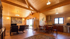 Un vaste espace de vie avec un plafond en bois, une table à manger avec des chaises, une cuisine équipée d’appareils modernes et un grand tapis.