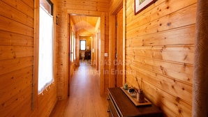 Un couloir en bois, avec une fenêtre sur la gauche, un tableau encadré sur la droite et une petite table au centre, sur laquelle se trouvent une bougie et des bâtonnets d’encens.