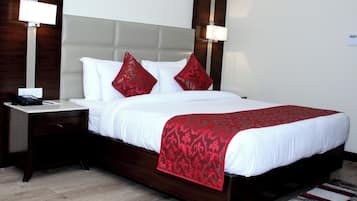 Una cama bien tendida con ropa blanca y roja, una mesita de noche de madera con una lámpara y un cabecero moderno.
