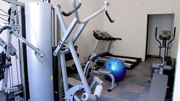 Un gimnasio con equipamiento de ejercicio, una cinta de correr y una pelota de gimnasia azul.