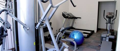 A gym with exercise equipment, a treadmill, and a blue exercise ball.
