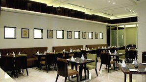 A modern restaurant with a long counter, booths, and a high ceiling with recessed lighting.