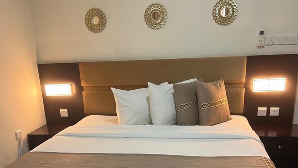 Une chambre d’hôtel avec un grand lit, une table de chevet et une lampe fixée au mur.