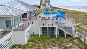 Un hotel frente a la playa con zona de piscina, mobiliario exterior y vistas a la playa.
