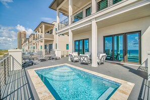Zona junto a la piscina con vista despejada al océano, piscina y edificio con balcones y amplias ventanas.