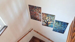 A wooden staircase with a handrail, leading to a landing with two wall-mounted artworks depicting trees. - Cosy house 6-8 people, near Strasbourg, quiet, garden, table tennis, hen (Wingersheim les Quatre Bans)