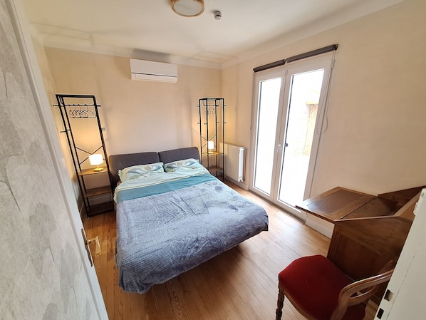 Une chambre à coucher comprenant un lit, un bureau, une chaise, un radiateur et une fenêtre donnant sur un paysage agréable.