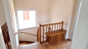 Una estrecha escalera con barandillas de madera y un pequeño escritorio de madera.
