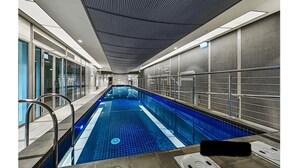 En inomhuspool med ett kaklat golv, metallräcken och ett tak med ett linjärt mönster.