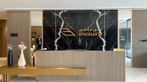 A reception desk with a marble back wall and a sign reading "BINGHATI". - Elegant 1BR Stay in Binghatti Heights (Dubai)