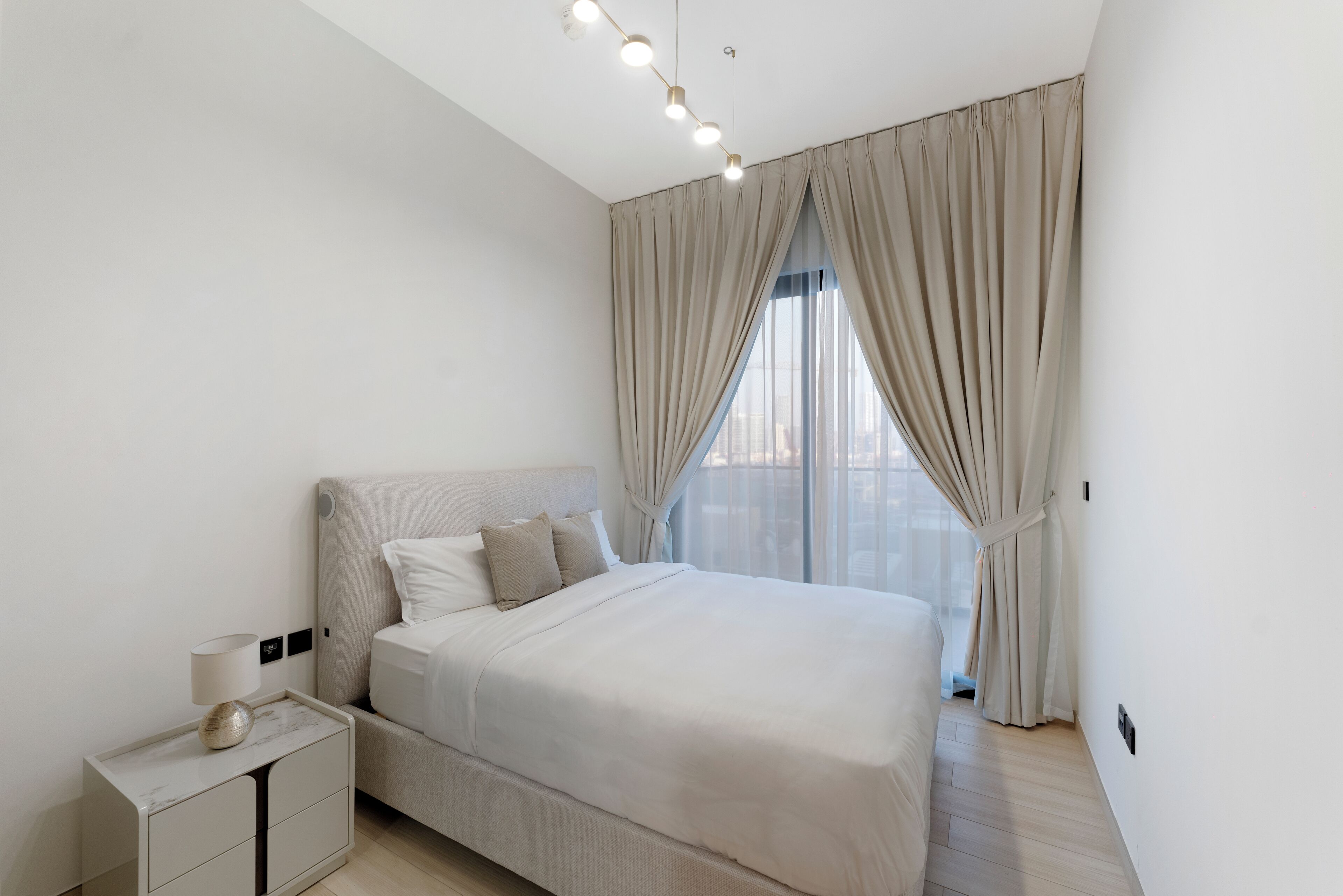 A modern bedroom with a large bed, a bedside table, and a ceiling light fixture.