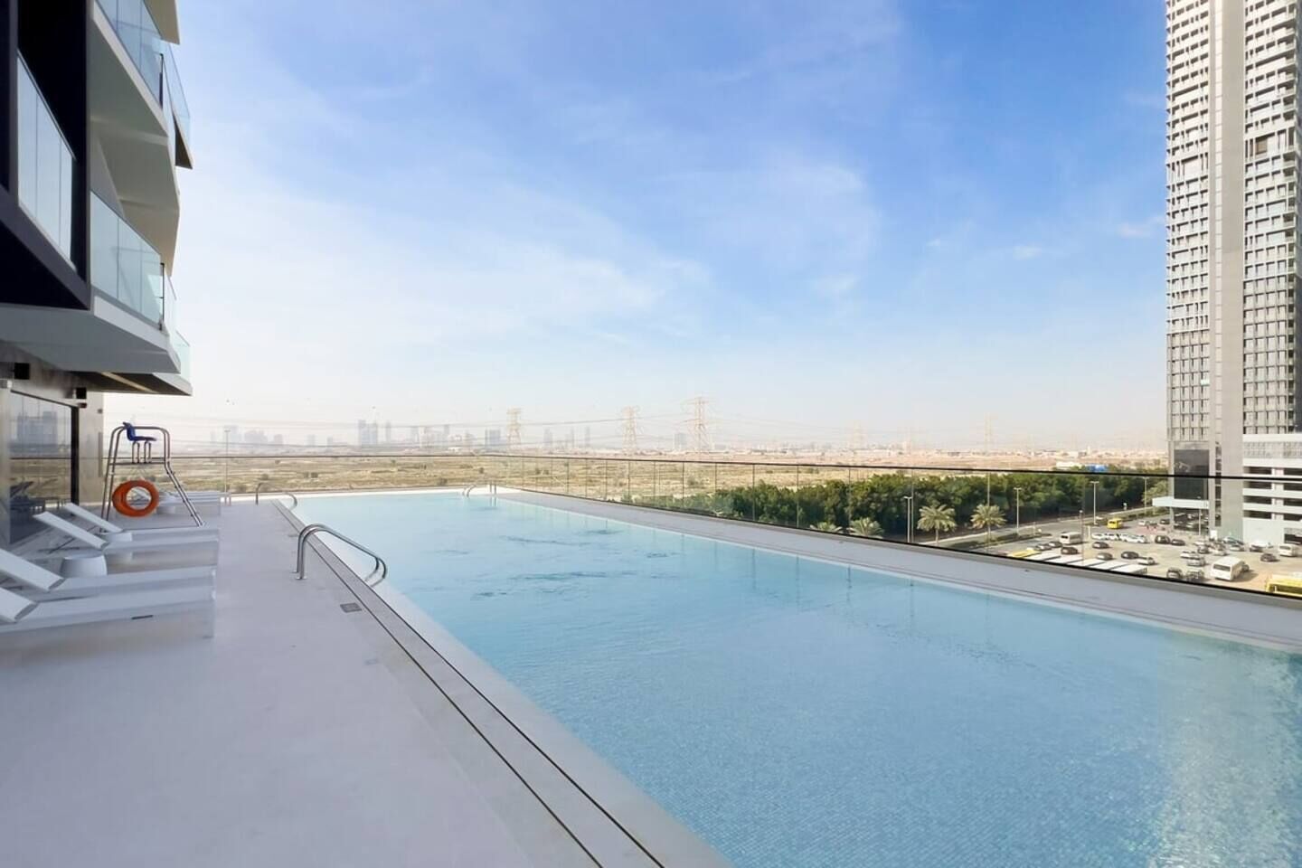 A rooftop swimming pool with a view of the cityscape and a high-rise building.