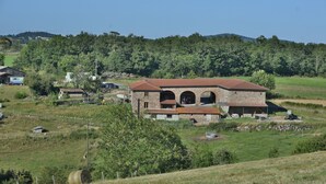Una casa de campo con fachada de piedra, entrada abovedada y tejado rojo.