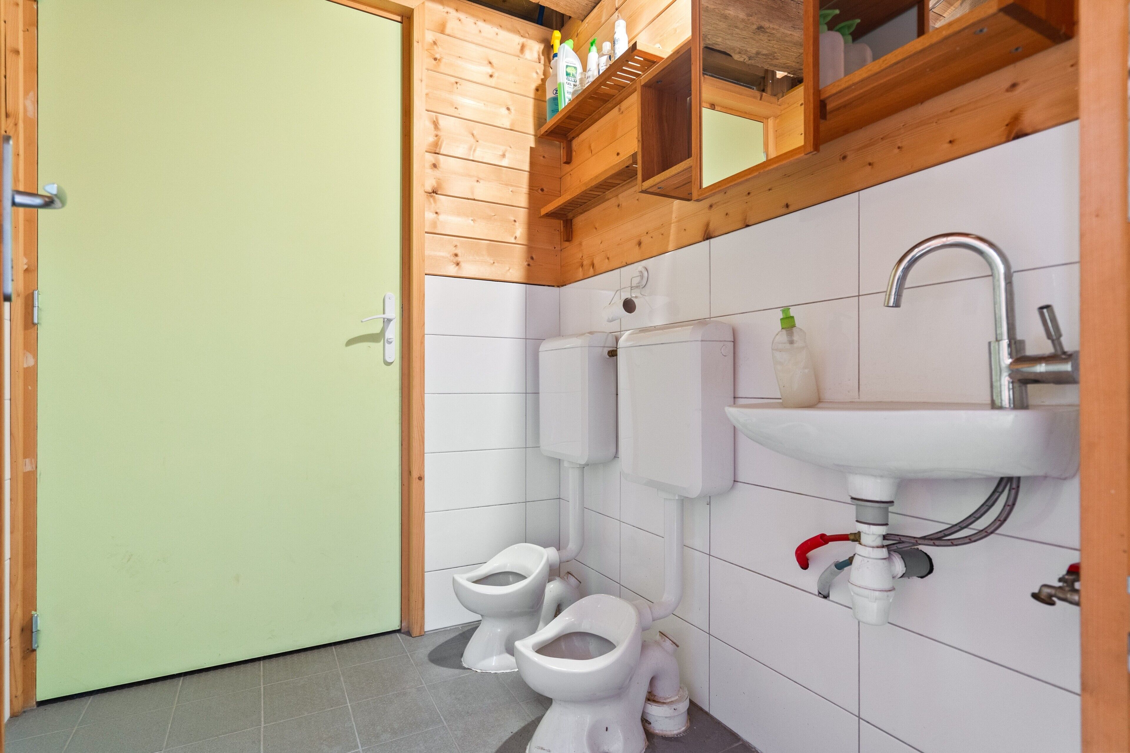 A bathroom with two toilets, a sink, and a wooden ceiling.