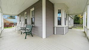 A covered porch with white wooden railings and a bench. - Welcoming 5-bedroom farmhouse in Rangeley (Rangeley)