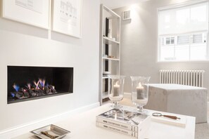 A modern living room with a fireplace, books, and decorative items. - Prime Knightsbridge Mews-4 bed House (London)