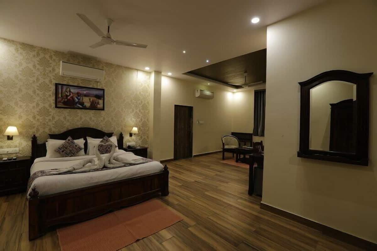 A bedroom with a bed, bedside tables, a ceiling fan, a wall-mounted air conditioner, a chair, and a mirror.
