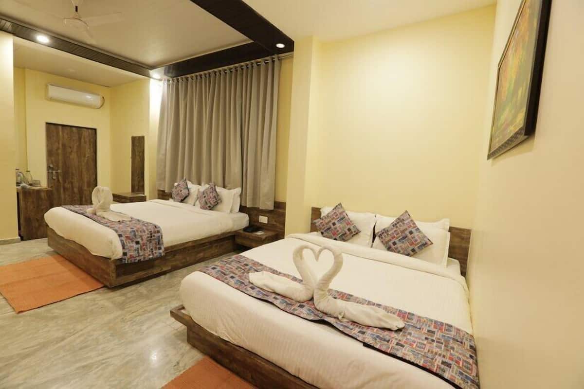 A hotel room with two beds, a wooden headboard, a large window with curtains, and a ceiling fan.