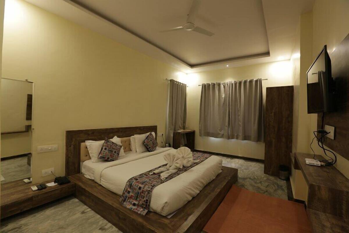 A hotel room with a bed, a TV, a ceiling fan, and curtains.