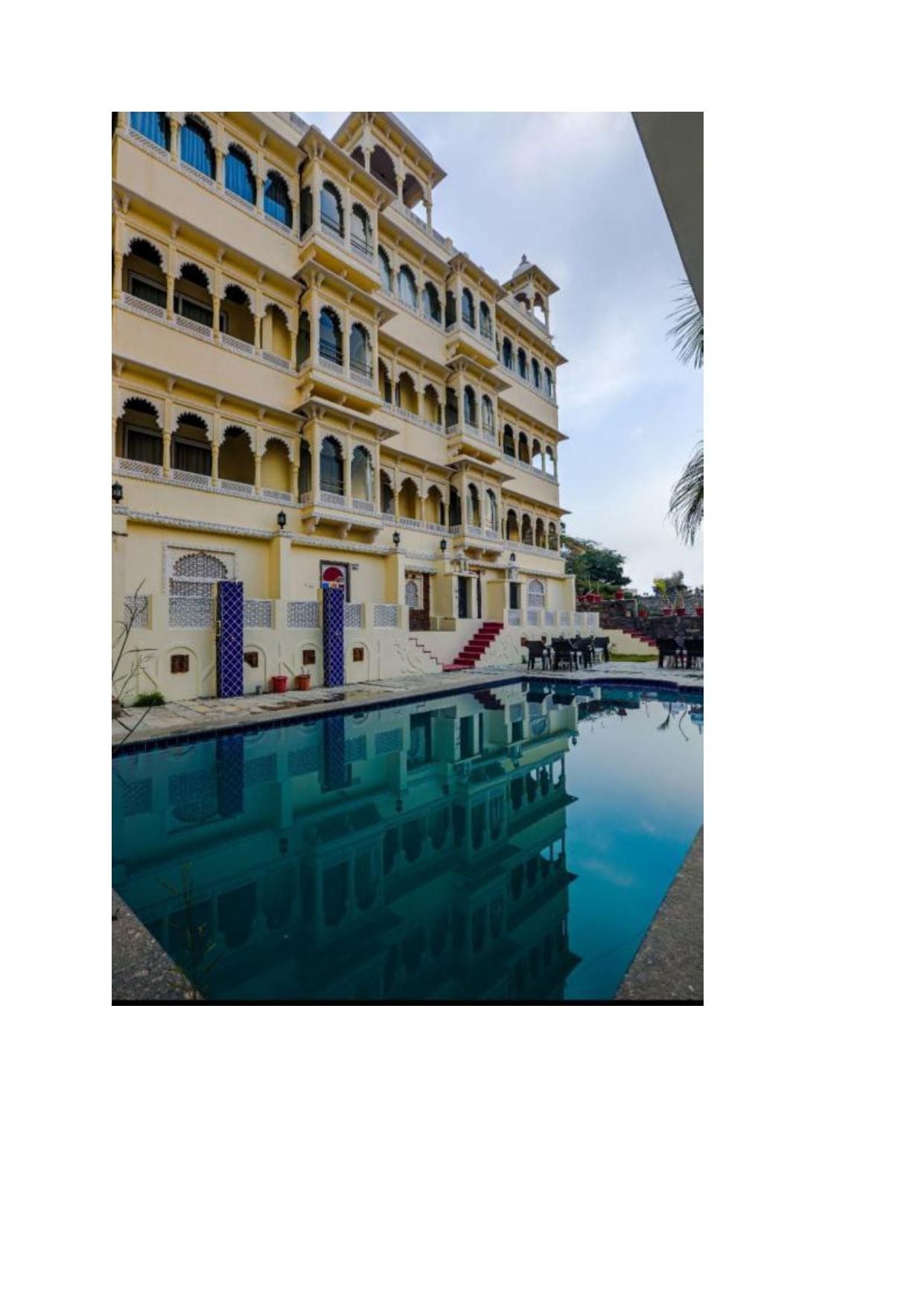 A multi-story building with a pool in front.
