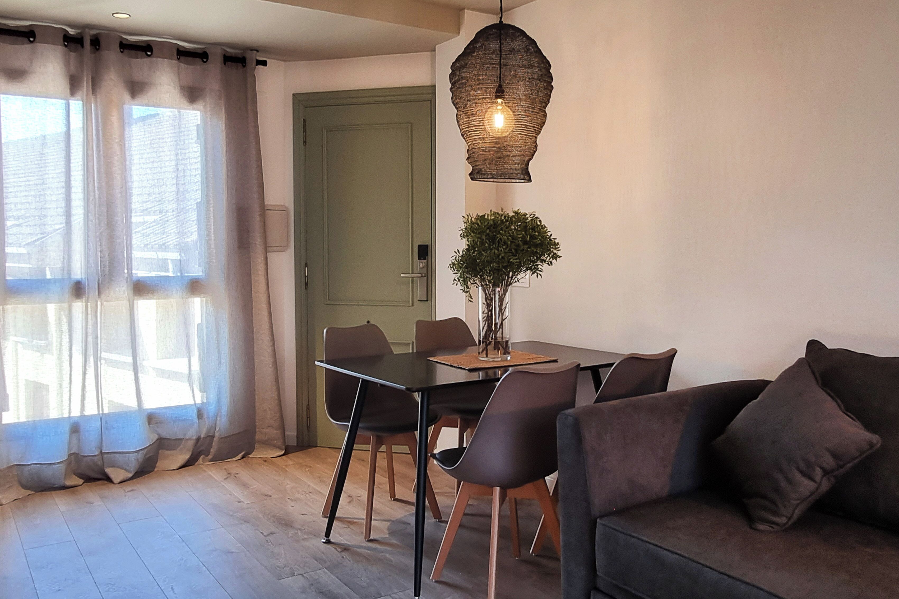 Un espace repas comprenant une table, des chaises et un luminaire suspendu.