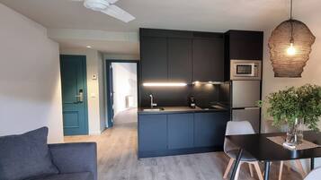 A modern kitchen with dark cabinetry, a microwave, and a hanging light fixture.