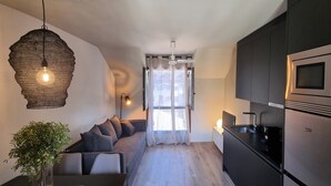 Una cocina moderna con armarios oscuros, un microondas integrado y un refrigerador de acero inoxidable.