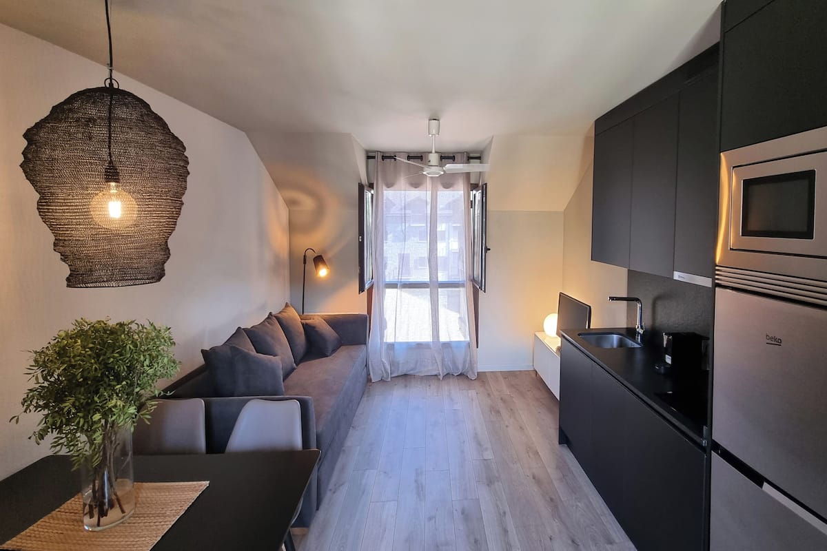 Una cocina moderna con armarios oscuros, un microondas integrado y un refrigerador de acero inoxidable.