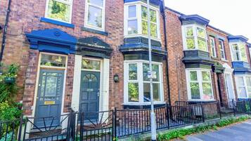 A row of terraced houses with bay windows and a black metal fence.