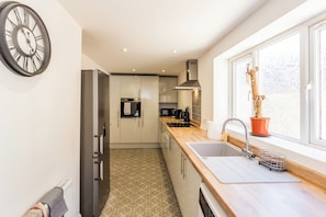 A modern kitchen with a built-in oven, a stainless steel refrigerator, and a window with a view of the outdoors.