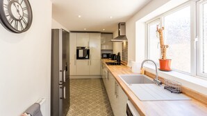 A modern kitchen with stainless steel appliances, a wooden countertop, and a window with a view.