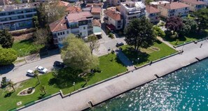 Vista aérea de una zona residencial con una orilla, que muestra edificios de varios pisos, un paseo pavimentado y coches aparcados.