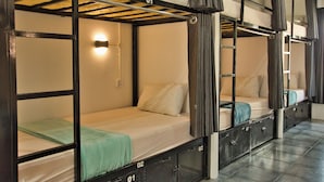 A dormitory-style room with bunk beds, a wall-mounted light, and a metal ladder. - Mad Monkey Kampot (Kampot)