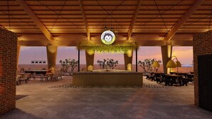 A spacious outdoor area with a wooden ceiling, a central seating area with tables and chairs, and a view of the sea. - Mad Monkey Kampot (Kampot)